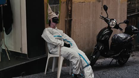 un maniquí surrealista de la calle descansando en una silla, callejón napolitano, italia