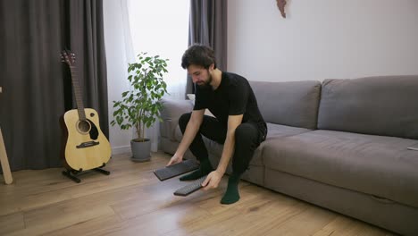 Man-at-living-room-preparing-for-standing-on-nails-barefoot