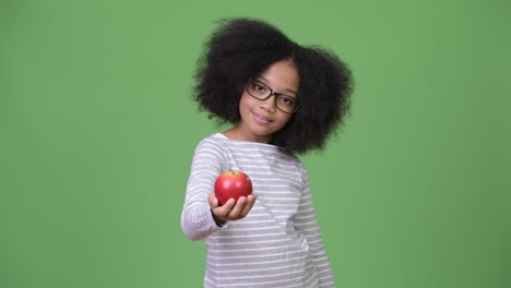joven africana feliz con cabello afro sosteniendo manzanas
