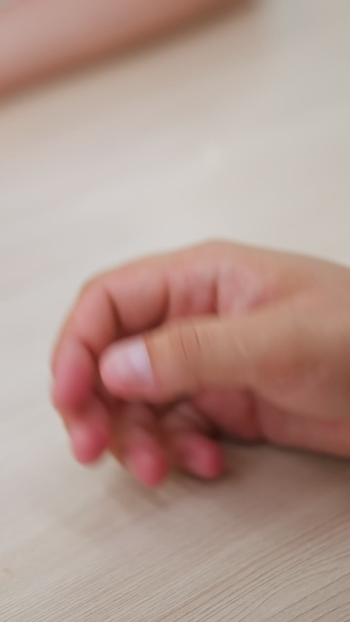 primer plano de una pareja que se toman de la mano afectuosamente, mostrando sus anillos como símbolo de conexión y amor, mientras las manos se encuentran tiernamente en la superficie lisa de la mesa de madera