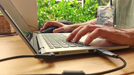 cerca de las manos escribiendo y desplazándose en una computadora portátil mientras estaba en un complejo de verano mostrando el estilo de vida de trabajo remoto sincero y genuino