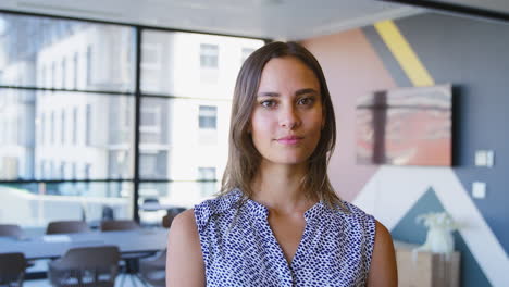 Portrait-Of-Smiling-Young-Businesswoman-Standing-In-Modern-Empty-Office