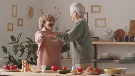 Cheerful-Senior-Couple-Cooking-and-Dancing-in-Kitchen