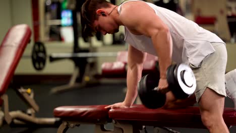 closeup side view of young bodybuilder doing one arm dumbbell rows