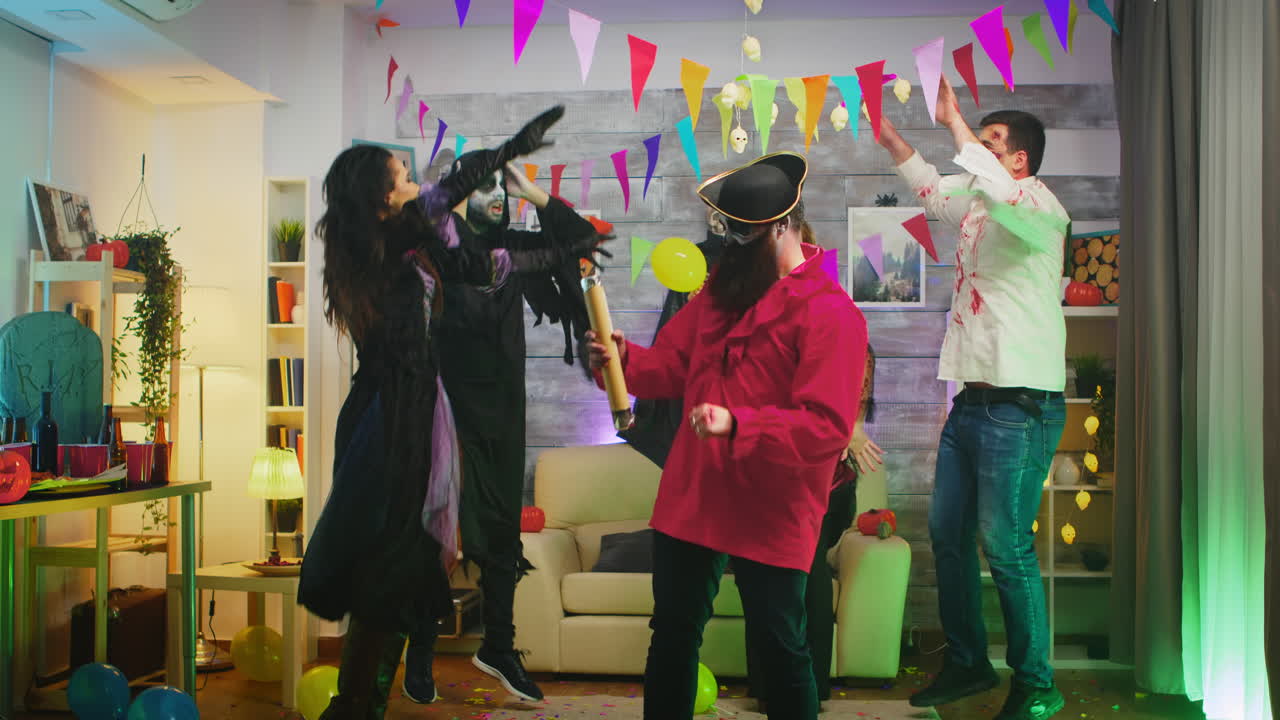 할로윈 파티에서 해적처럼 옷을 입은 수염이 있는 남자가 콘페티를 폭발시키고 있다.