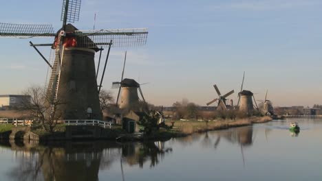 a boat moves along a canal in holland with windmills nearby 2