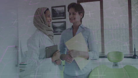 two women discussing in office with digital data processing animation overlay
