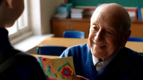 elderly man happily receives a handmade card in a classroom setting