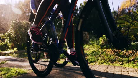 pareja de ciclismo de montaña montando en el bosque en un día soleado