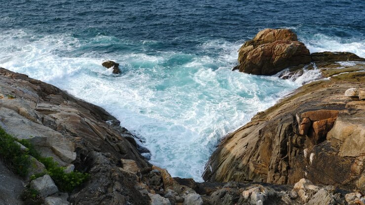 Onde selvagge dell'oceano si infrangono su una costa rocciosa. Statico.
