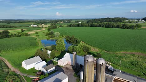aerial rising of american. farmstead with tractor, equipment and silo storages. sunny summer day in america. house in suburb of town