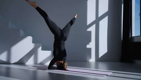 vrouw die een headstand yoga pose doet