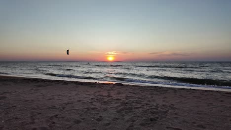 Un-Windsurfista-Se-Desliza-Con-Gracia-Sobre-Las-Tranquilas-Aguas-Del-Mar-De-Azov-Mientras-Se-Pone-El-Sol,-Proyectando-Hermosos-Tonos-En-El-Cielo.