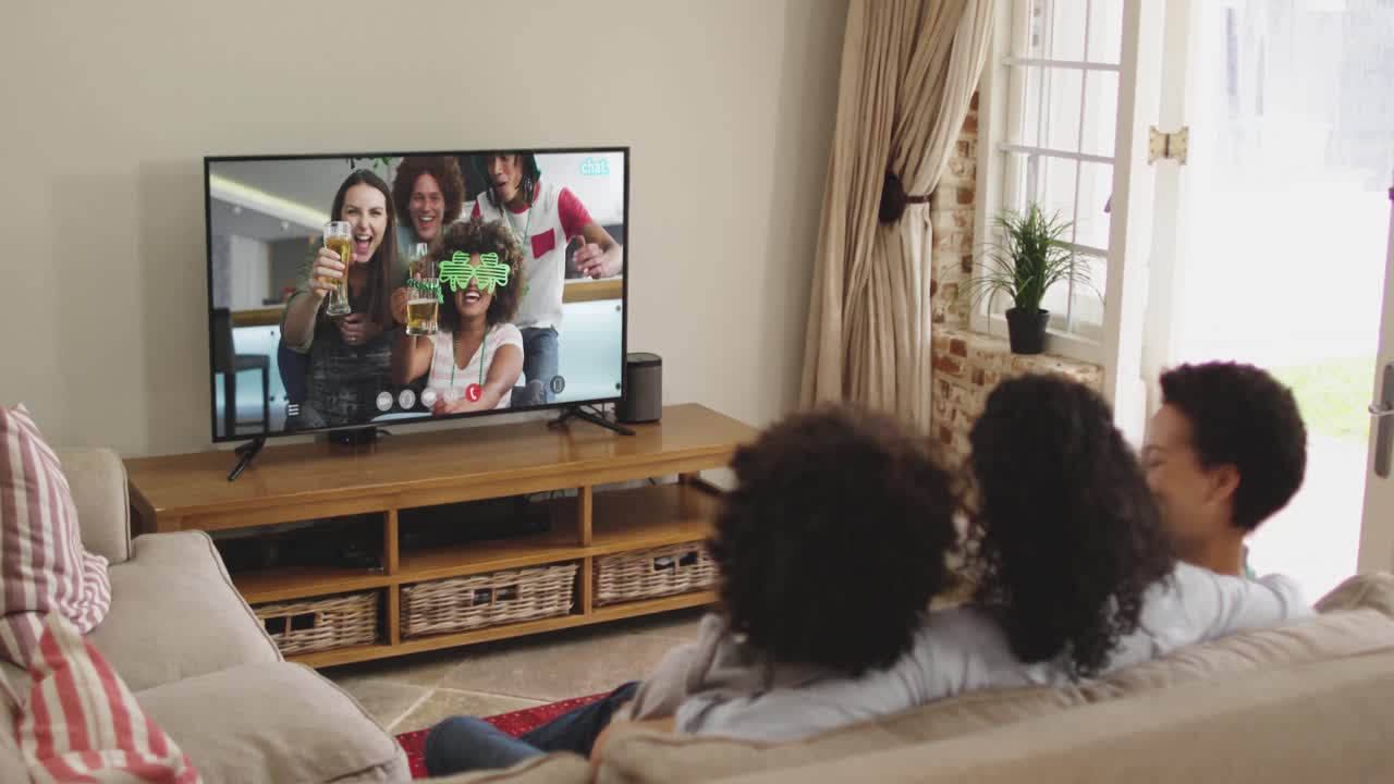 Famiglia afroamericana a casa che usa la smart TV per fare una videochiamata nel giorno di San Patrizio.