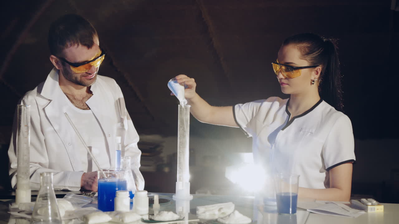 Two scientists are working in laboratory. Young female researcher and her senior supervisor are doing investigations with test tubes.