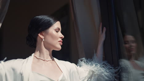 woman in a white robe by the window