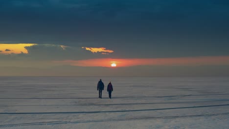 the man and woman with backpacks walking through the icy lake