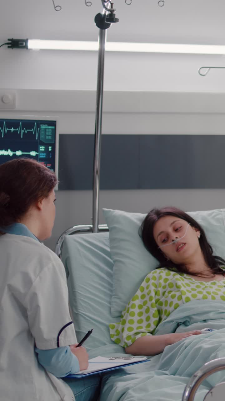 Vertical video: Black nurse typing disease symptom while specialist practitioner doctors checking sick woman