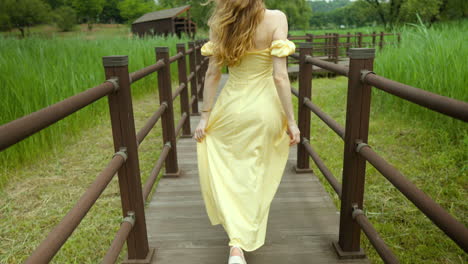 Blonde-caucasian-pretty-woman-walking-happily-through-wooden-planks-in-countryside