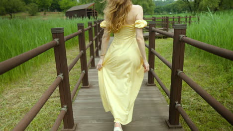 blonde caucasian pretty woman walking happily through wooden planks in countryside