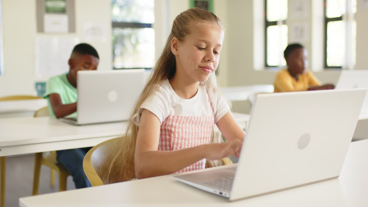 Compagni di classe, una bambina sposta lo sguardo verso il laptop, digitando e parlando per rispondere a una domanda.