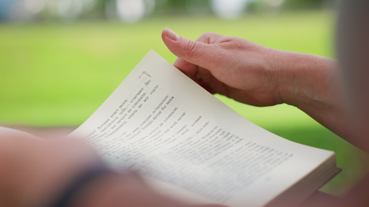 Close up of book pages turning softly under sunlight with blurred green background, delicate motion symbolizing curiosity, learning, discovery, and calm mindfulness