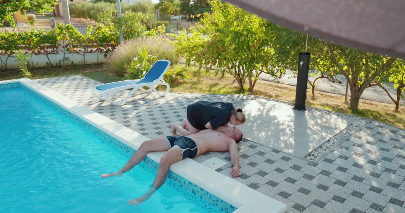 Woman performing CPR and attempting to revive an unconscious man beside a swimming pool after a water accident, representing drowning rescue and emergency first aid.