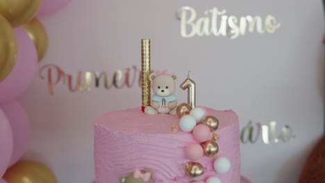 close up of first birthday cake with teddy bear number one and festive colors