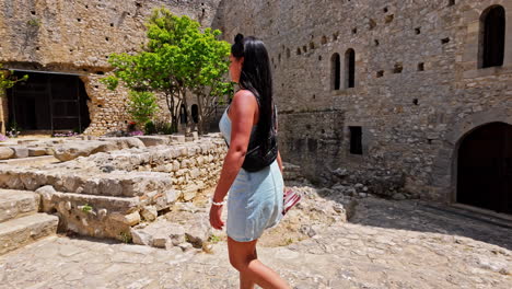 European-female-tourist-strolls-near-Chlemoutsi-Castle-Museum,-admiring-its-historic-beauty