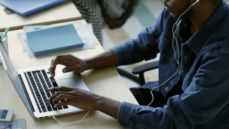 Man Listening to Music with Headphones and Using Laptop