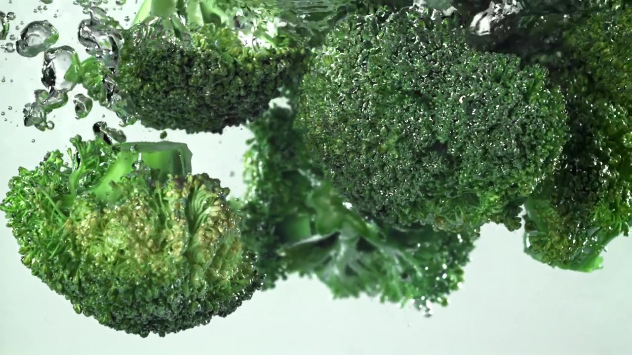 Broccolo verde fresco che cade nell'acqua al rallentatore