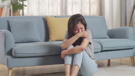 young asian woman victim of violence with bruise on body crying being hurt from physically abused while sitting on the floor at home