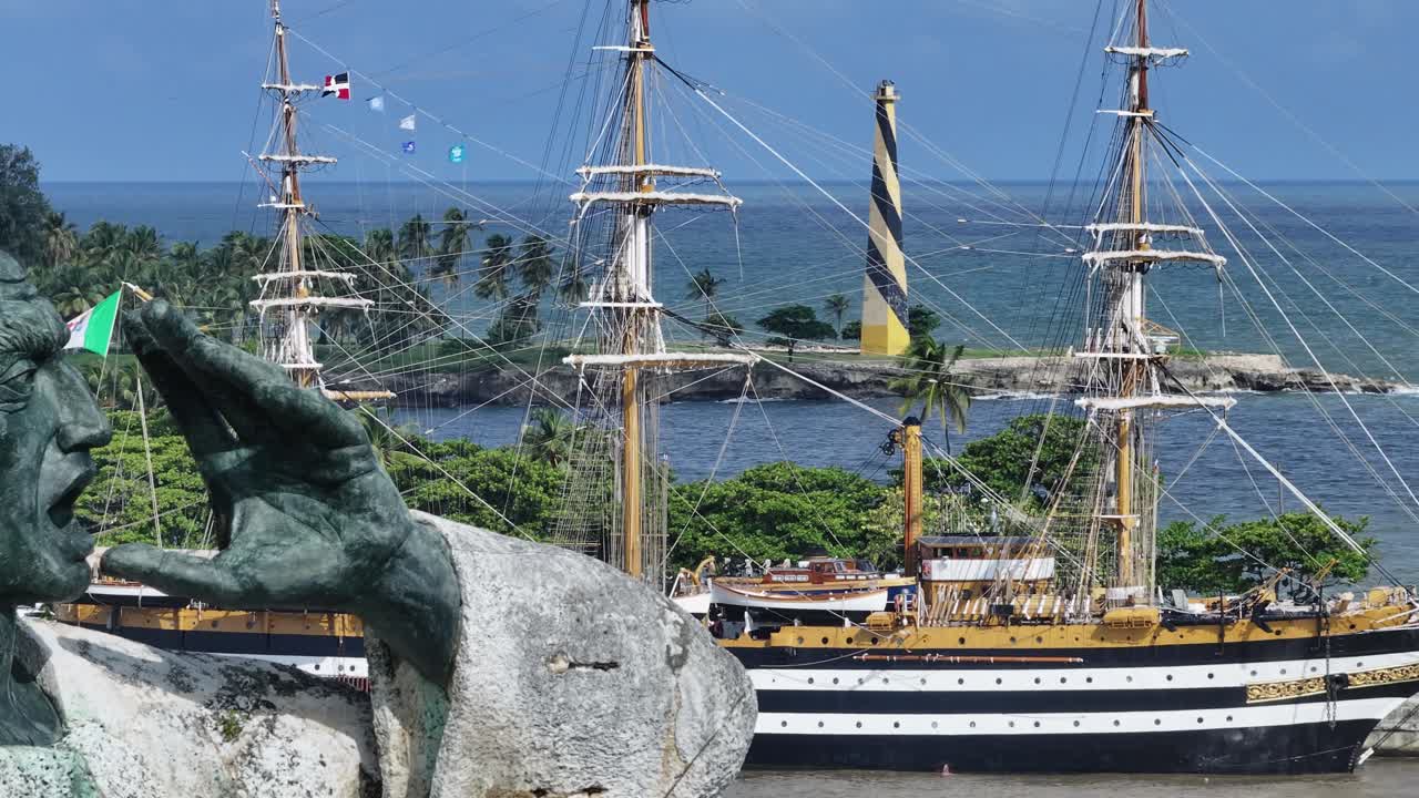 아메리고 베스푸치 (amerigo vespucci) 라는 이름의 이탈리아 훈련 선박과 함께 산토 도밍고 항구의 동상을 보여주는 드론  ⁇