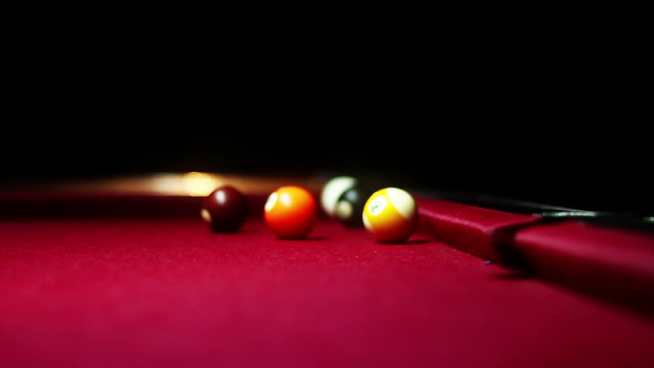 Boules de billard reposant sur une table de billard rouge en lumière tamisée.