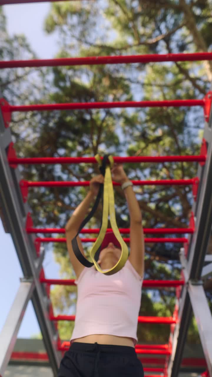 Woman using resistance band on outdoor gym equipment