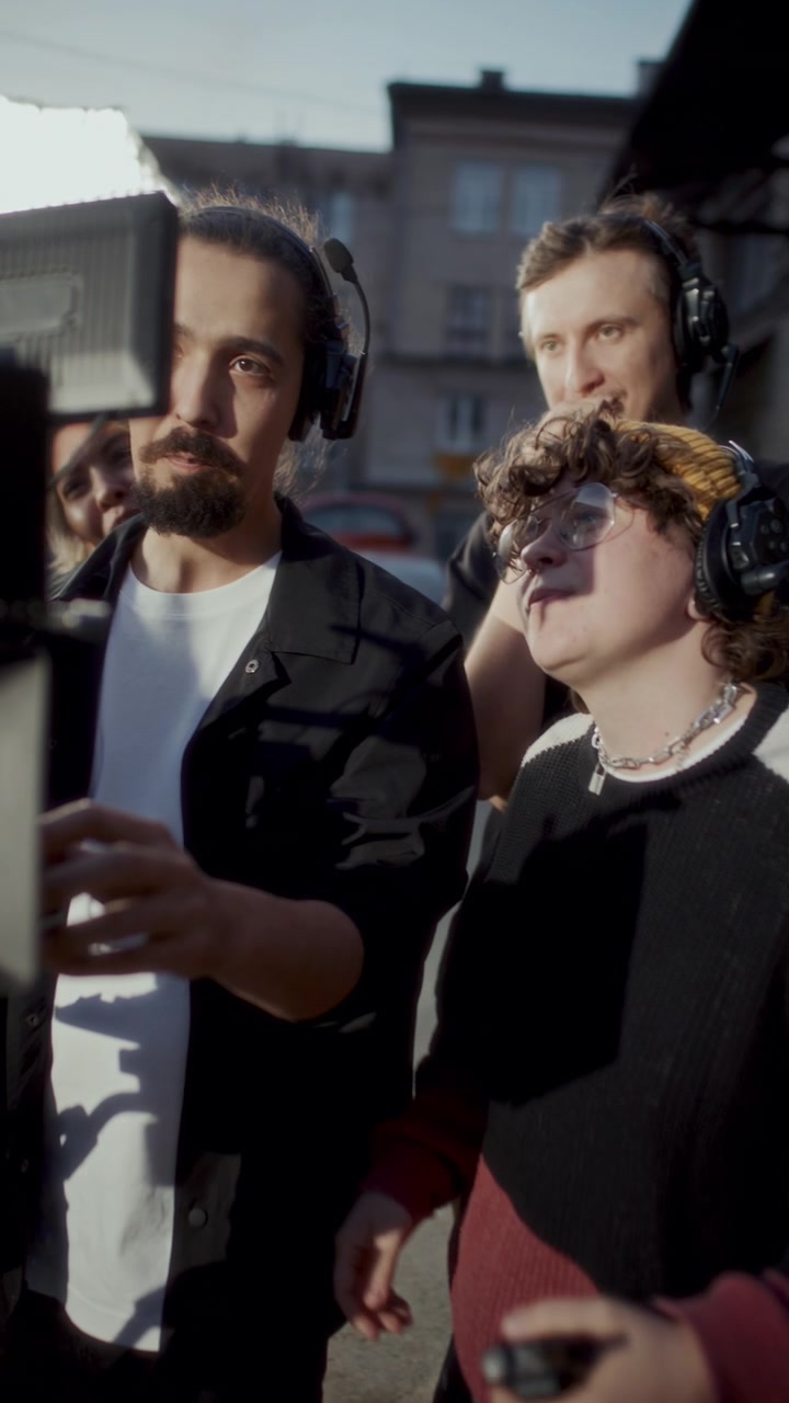 Videógrafo Ajustando Rig de Cámara, Rodeado por Equipo de Rodaje en Set Exterior