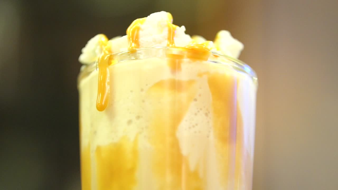 Primo piano di un milkshake appena fatto con caramello che cola lungo il bordo del bicchiere
