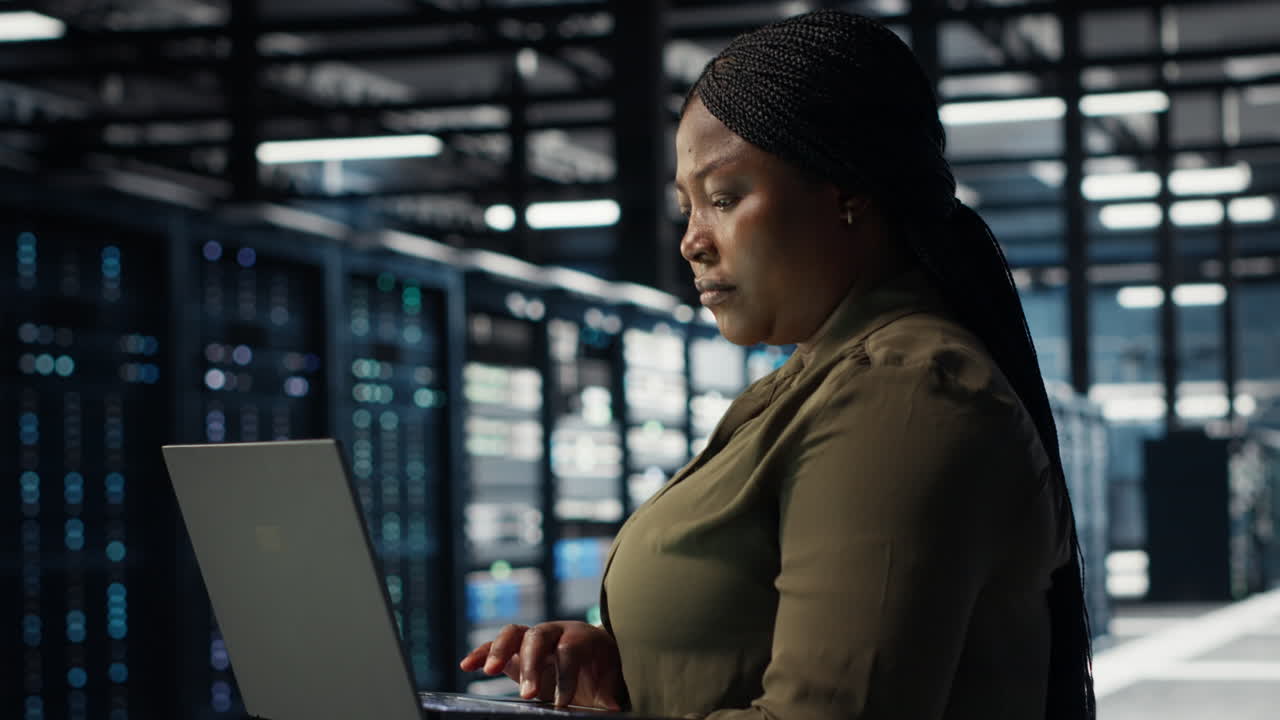 Technician using laptop in high tech data center, integrating new technologies