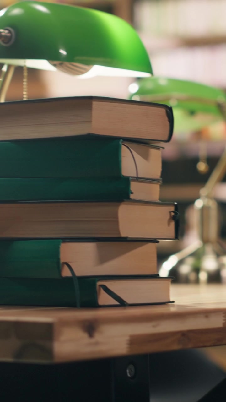 Vertical Video Pile of hardcover books on wooden desk in empty college library