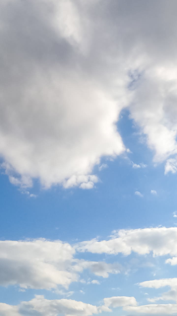 Stunning azure sky with brightly shining sun and soft cloudscape. White fluffy clouds quickly changing shapes in the atmosphere. Timelapse. Vertical video