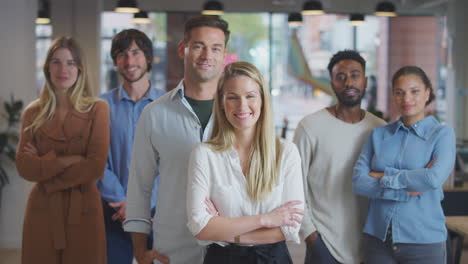 portrait of multi-cultural business team standing in modern open plan office