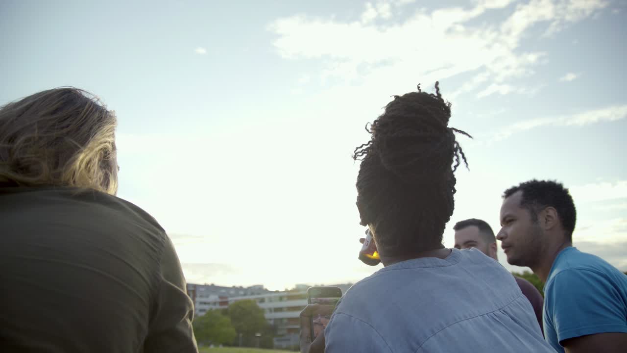 Young people cheering with beer bottles and taking photo.