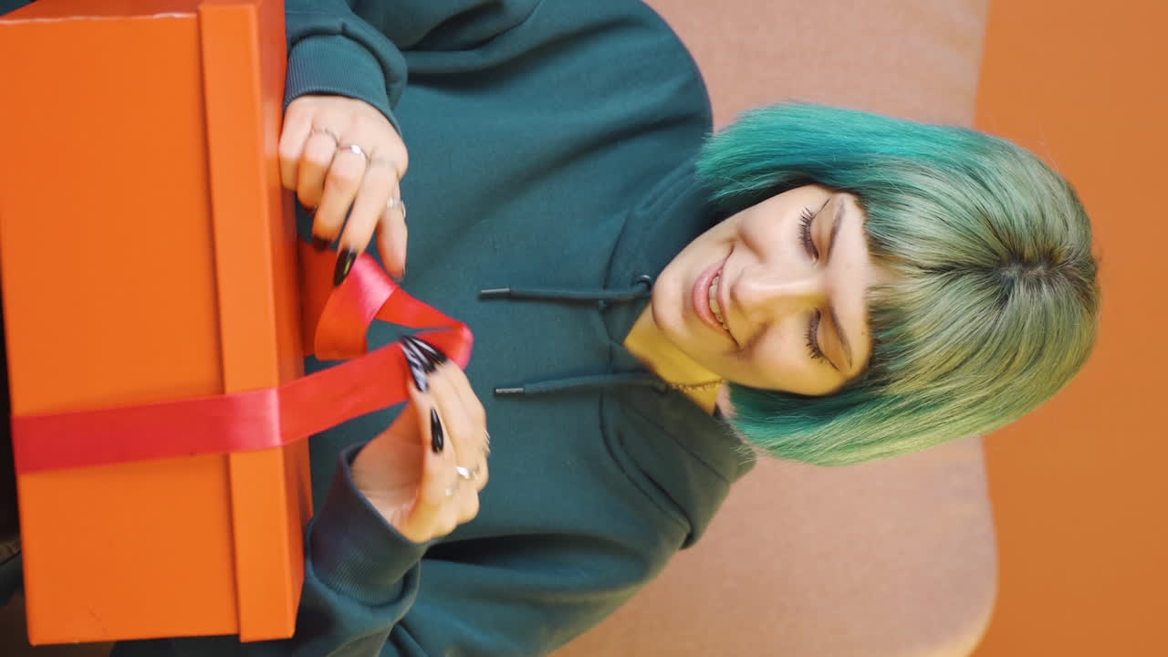 Video verticale di giovane donna felice e gioiosa che apre un pacchetto regalo