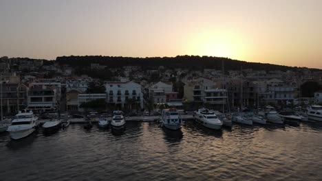 Skyline-city-and-harbor-Argostoli,-Greece,-aerial-sideways-with-golden-sunset