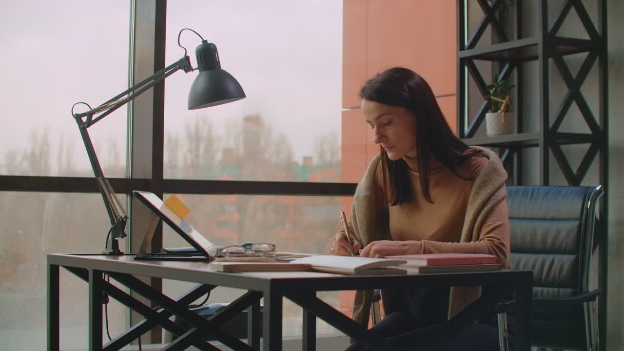 A female graphic designer works in an office with large Windows and paints using a stylus and a computer touch screen. Workstation with touchscreen for designers. Come up with and develop the concept of the logo.