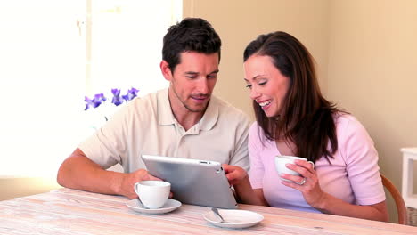 Feliz-Pareja-Charlando-En-La-Mesa-Usando-Tablet-Pc