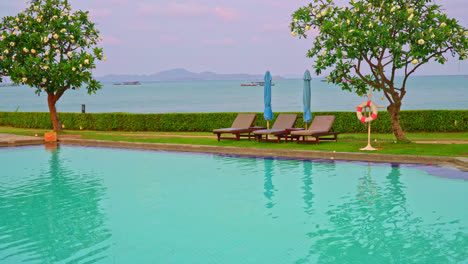 chair pool  or bed pool and umbrella around swimming pool with sea background - holidays and vacation concept