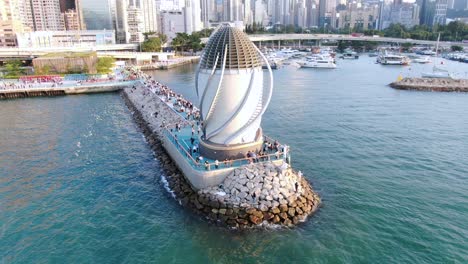 people walking on a breakwater with central wanchai bypass east vent shaft in causeway bay, hong kong