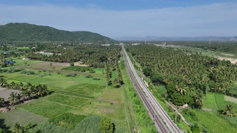 Aerial-footage-of-the-service-lanes-alongside-the-main-highway-used-by-local-traffic-with-railway-passing-train