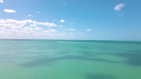 disparo de drone de gran angular acercándose a un barco que conduce en las aguas cristalinas de color turquesa frente a la costa de la isla de holbox en el mar caribe ubicado en méxico filmado en 4k